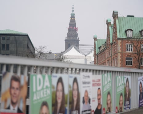 Denmark's flags fly atop the Danish Parliament building, Christiansborg Palace, behind election posters on the morning of the parliamentary election, in Copenhagen, Denmark.