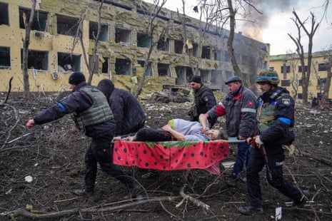 Kalinina is carried on a stretcher by five male emergency workers with a blown-out three-storey building behind