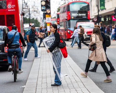 Woman stands in raised area in middle of busy street holding clothes drier
