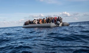 Migrants sit in a rubber dinghy