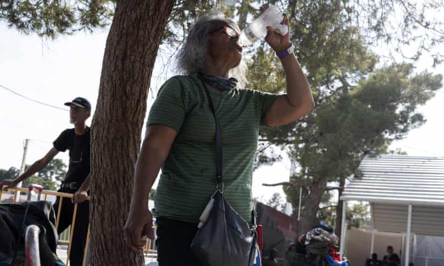 A woman with gray hair drinks from a water bottle outside a homelessness resource center in Las Vegas.