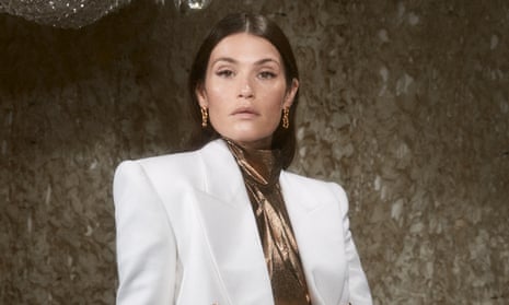 Gemma in a white suit against a gold background