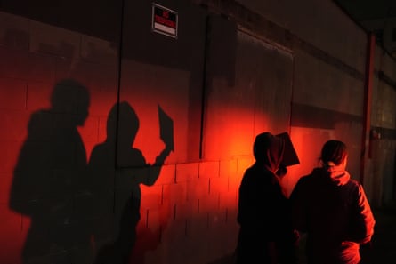 Two protesters are lit by a police light as they walk outside an ICE facility in Portland in January 2026.