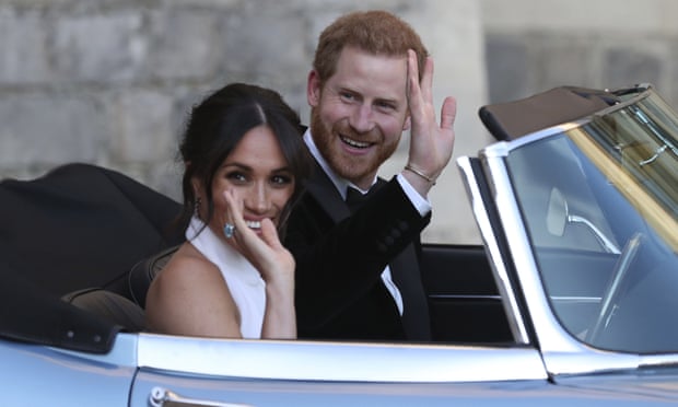 Harry and Meghan waving from open top car.