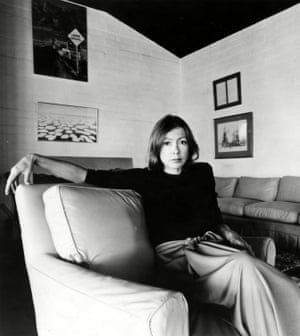 A black and white portrait of Joan Didion sitting in an armchair at her home.