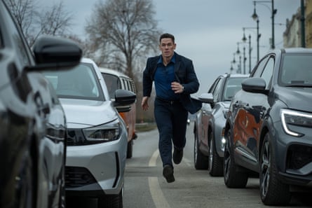 A man in a suit running between cars in a traffic jam