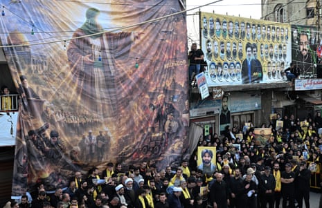 Crowds of people carrying Hezbollah flags and banners at a funeral procession.