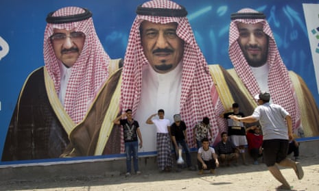 Saudi boys play in front of a billboard showing King Salman flanked by Mohammed bin Salman (right) and Mohammed bin Nayef.