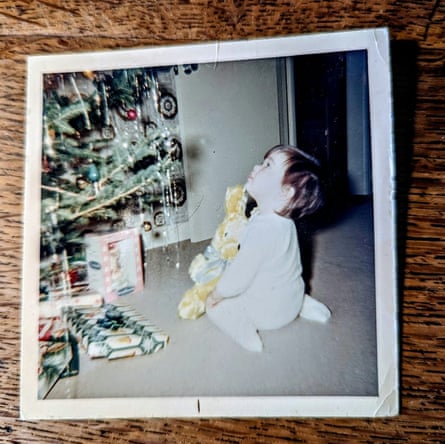 A baby staring up at a Christmas tree.