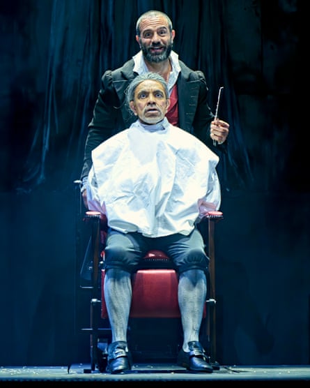 Ramin Karimloo as Sweeney Todd stands behind David Bedella as Judge Turpin, seated in a barber’s chair.