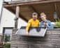 A couple install a solar panel on a wooden balcony