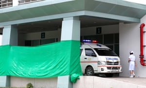 A nurse walks past an ambulance at a covered area of the Chiangrai Prachanukroh Hospital