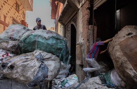 Two men manoeuvre huge bags of rubbish on a street