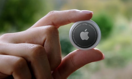 hand holds round, small airtag with apple logo