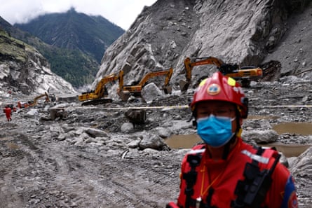 A rescue worker stands near excavators at the core disaster-hit area at Gyirong Port