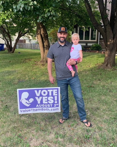 Seth Simmons, 37, stands in his front yard with his daughter and his yes sign.