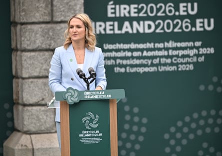 Helen McEntee speaks at an event outside Dublin Castle. She is 40 and has long blond hair styled in loose waves. She wears a pale blue jacket.