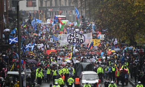 Large crowd, police in hi-vis jackets, Scottish flags, banner reads Net Zero. Climate protesters gather for the Global Day of Action for Climate Justice march in Glasgow.