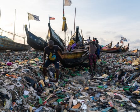 Barcos de pesca em uma praia coberta de resíduos têxteis