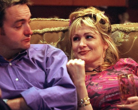 Craig Cash and Caroline Aherne sit together on a sofa in The Royle Family