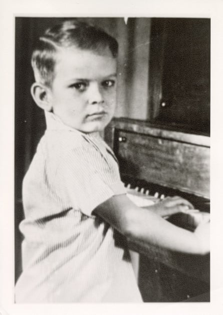A black-and-white image of a boy sitting at a piano.