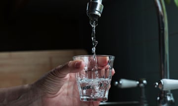 A person fills a glass under a tap