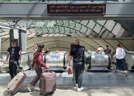 Commuters are warned about the hot weather outside the Canary Wharf station in London.