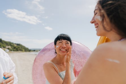two women applying sunscreen at the beach