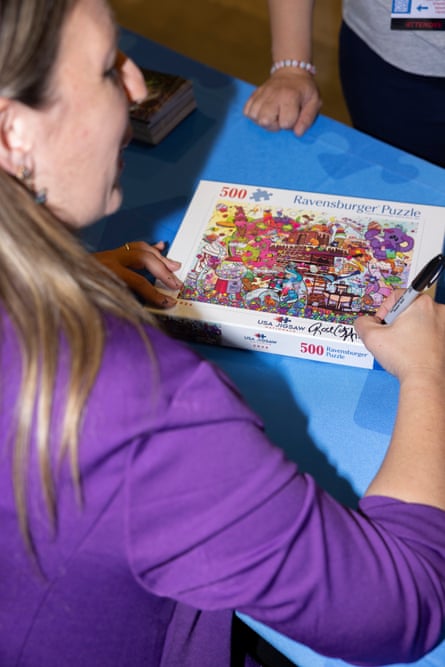 A woman in purple signing a puzzle box.