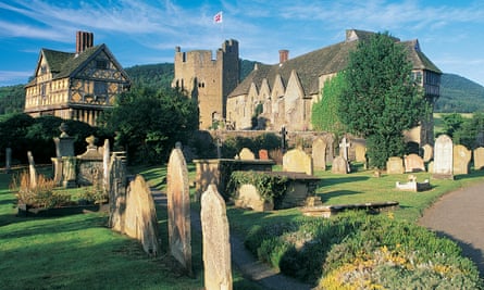 A cemetery with gravestones in dappled light; in the background the buildings of Stokesay Castle