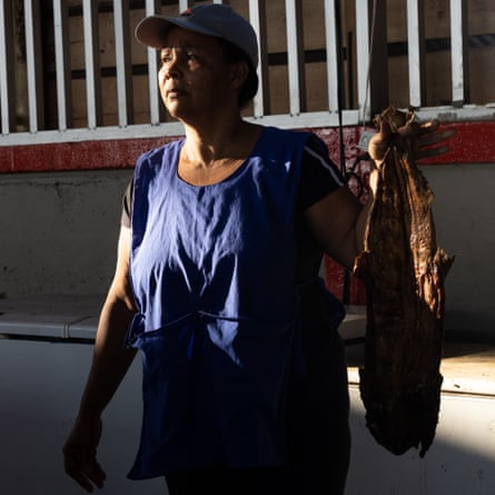 A woman in a cap holds up smoked fish in the market square