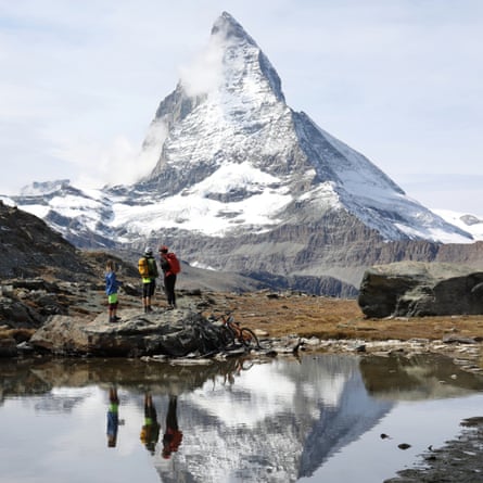 Mountain bikers pause at end of alpine lake in front of the Matterhorn