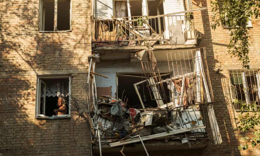 A man stands by a window inside his damaged apartment after shelling at a residential area in Mykolaiv.