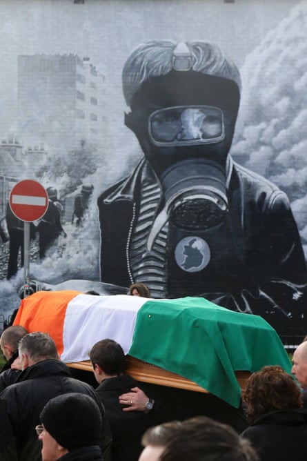 The funeral procession passes a mural in Bogside.