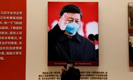 A visitor stands near an image of Xi Jinping during an exhibition on coronavirus at the Wuhan Parlorr Convention Center.