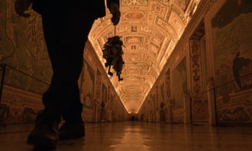 A man with a large bunch of keys walks down a long corridor in the Vatican Museums