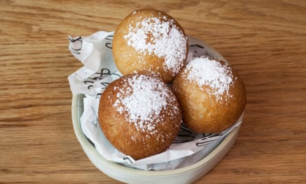 Three dulce de leche donuts with a layer of powdered sugar in a small pie bowl.