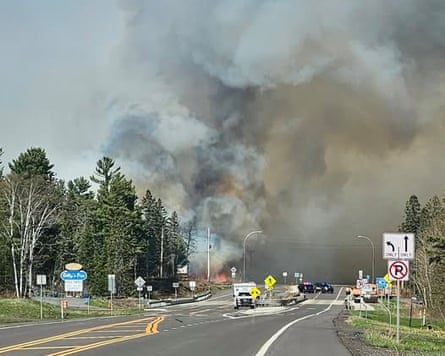 emergency vehicles on highway as smoke rises in grey sky