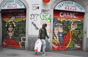 A man wearing a protective mask walks past a closed Chinese restaurant in Milan