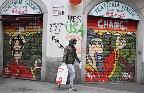 A man wearing a protective mask walks past a closed Chinese restaurant in Milan