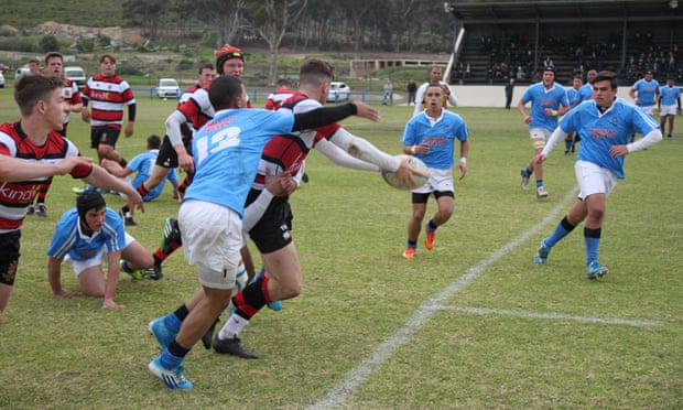 Going in for the tackle during a secondary school rugby match.