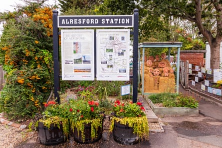 A noticeboard above flower planters at the entrance to Alresford railway station.