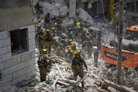 Soldiers walk amid the wreckage of bombed-out buildings.