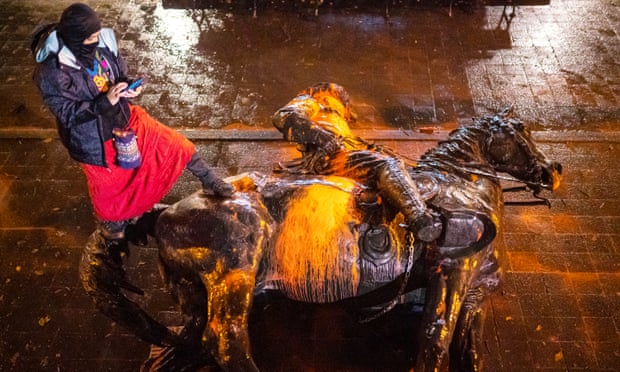 A protester stands over a toppled statue of Theodore Rosevelt during a protest Sunday in Portland, Oregon. 