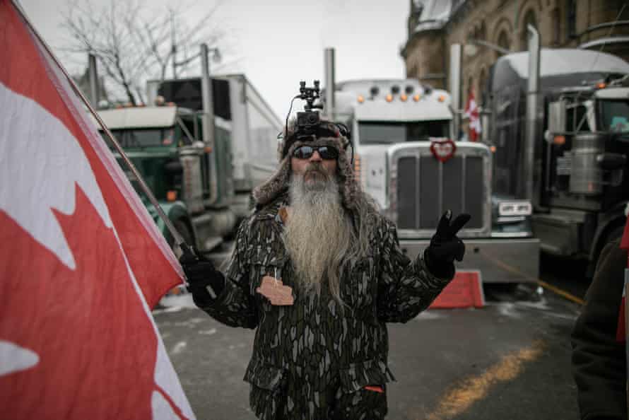 Supporter of the ‘freedom’ convoy stands with a Canadian flag in front of the parliament hill in Ottawa on Thursday.