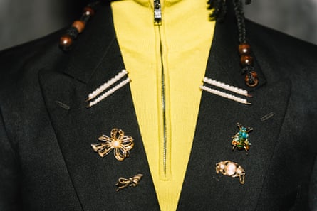 Close up on blazer with interesting pins over yellow shirt