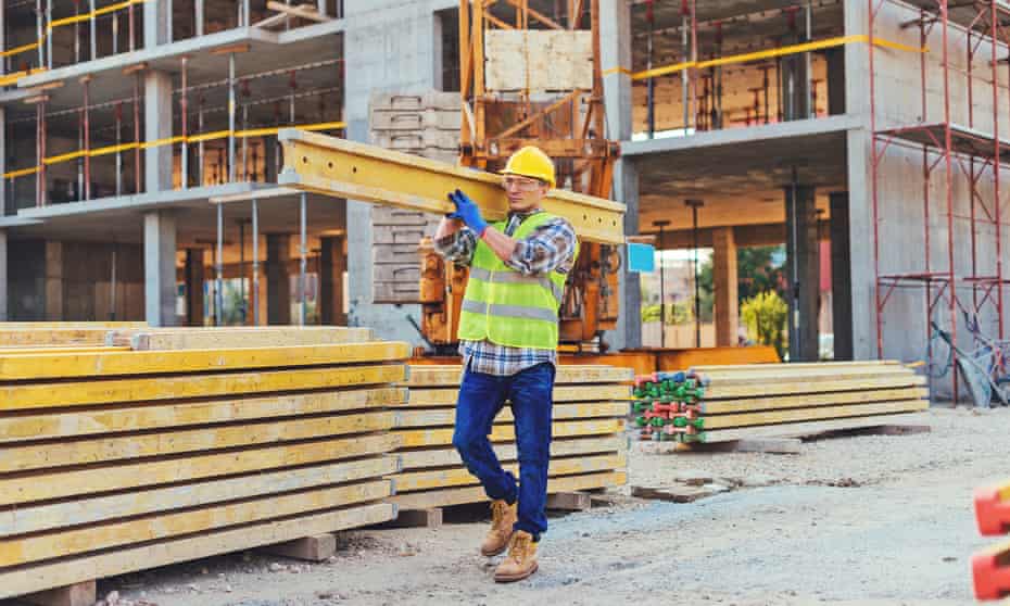 Stock image of a construction worker carrying a girder