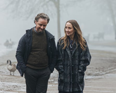 man and woman walk outside during winter, slushy snow on the ground behind them