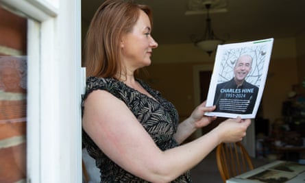 Kerry Hine stands in a doorway holding a magazine open with a photo of her husband on the page