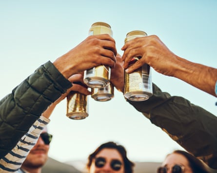 Low angle shot of a group of young friends cheersing with beers while enjoying their day out on the beach